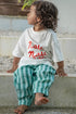 Nasi kids tee in white shirt with red text and green striped linen pants made by eco kids brand.