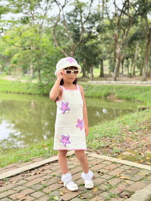 Child wearing a dress with starfish patterns outdoors near a pond