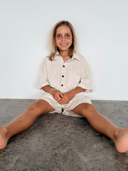 Person sitting on a gray floor with a white wall background
