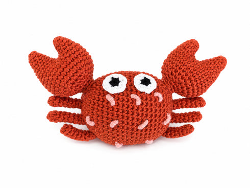 A crocheted crab toy in a rust-orange color, featuring large white eyes with black centers and small pink stitched details, set against a plain white background.