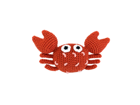 A crocheted crab toy in a rust-orange color, featuring large white eyes with black centers and small pink stitched details, set against a plain white background.