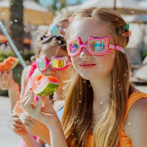 Children wearing colorful sunglasses eating watermelon outdoors.
