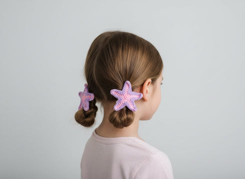 Child with star-shaped hair clips in a bun against a plain background