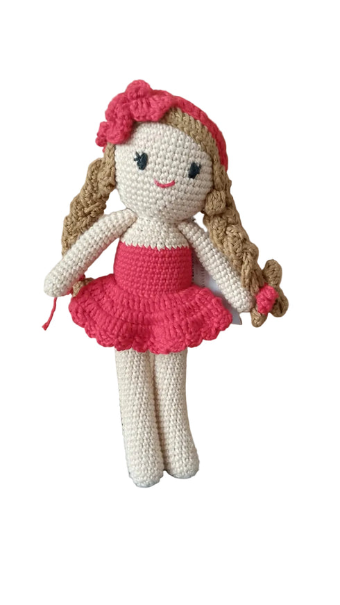 Crocheted doll with a red dress and headband on a wooden background