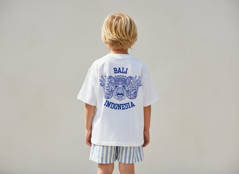 Child wearing a white t-shirt with 'Bali Indonesia' design on the back, standing against a plain background.