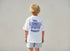 Child wearing a white t-shirt with 'Bali Indonesia' design on the back, standing against a plain background.