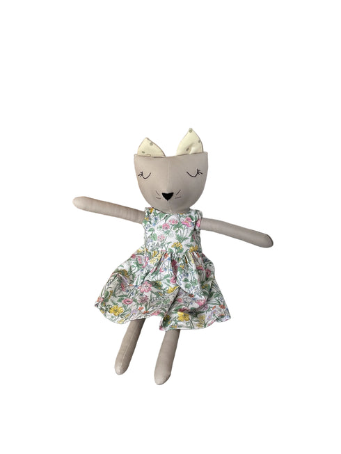 A handmade plush doll with a gray face and limbs, wearing a floral print dress
