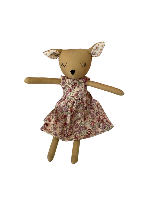 A handmade doll with a beige deer-like head, patterned ears, and a flowery dress