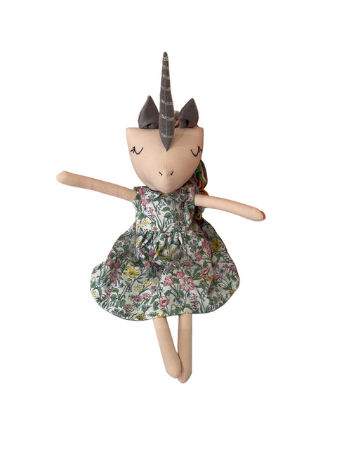 A handmade plush doll with a pale peach face and limbs, wearing a green floral dress.
