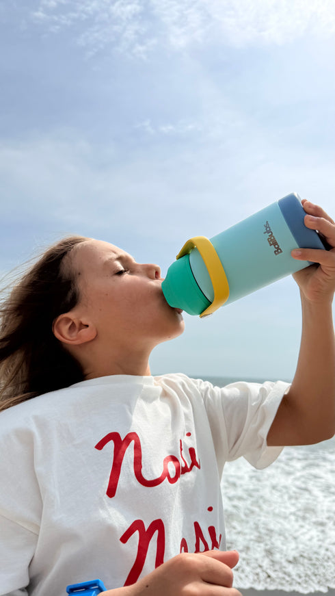 Person drinking from a colorful water bottle against a clear sky.