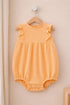 Yellow baby romper on a wooden hanger against a beige wall