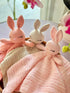 Three crocheted bunny security blankets in pastel pink, cream, and light pink