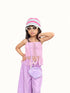 A young girl modeling a pink and white striped crochet bucket hat, white sunglasses, a pink crochet fringed tank top, lavender pinstriped pants, and a matching purple crochet crossbody bag against a plain white background.