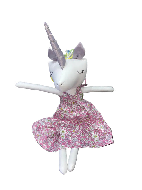 Stuffed unicorn toy with a floral dress sitting
