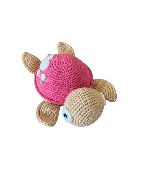 Crocheted turtle toy with pink shell on a gray surface