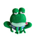 Crocheted green frog toy with a striped shirt on a reflective surface