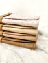 Stack of folded blankets in beige and brown on a white surface