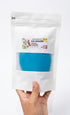 Hand holding a package of blue play dough with a visible brand label on a white background