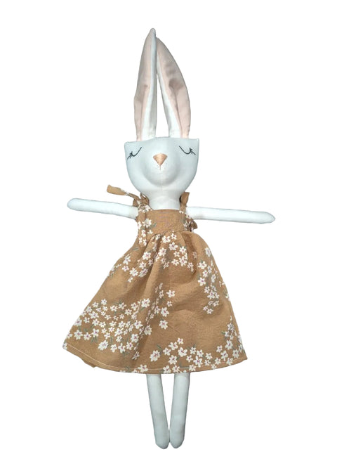 A handmade plush bunny doll with long white ears, a white face and limbs, wearing a brown dress with a white floral pattern.