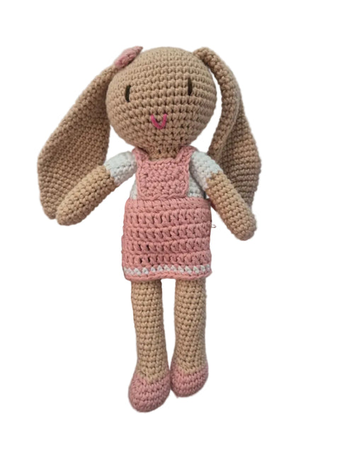 A handmade crocheted bunny doll with long tan ears and a pink dress.
