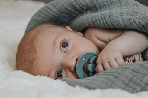 Newborn baby resting with a BIBS Colour pacifier in Sage