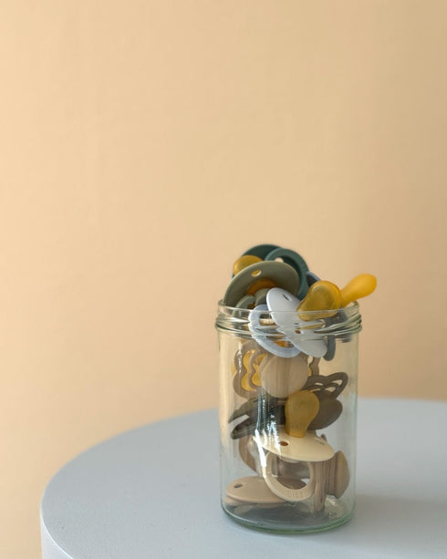 Glass jar filled with BIBS pacifiers in mixed colours
