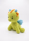 A crocheted dragon toy in light green, featuring light blue wings, blue and orange hair spikes, and small black embroidered eyes