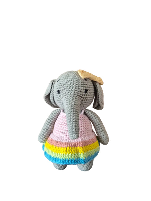 A crocheted elephant toy wearing a pastel dress with pink, yellow, and blue stripes