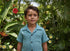 Child in a blue shirt standing in a lush garden with flowers and greenery
