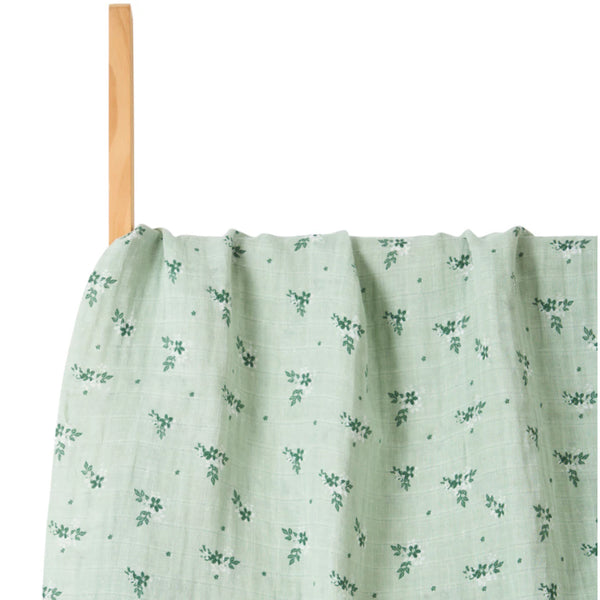 Green fabric with floral pattern on a wooden stick against a white background