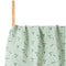 Green fabric with floral pattern on a wooden stick against a white background
