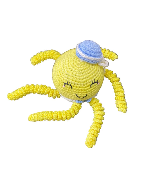 Yellow knitted toy with a blue hat on a dark surface