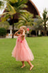 a light pink sleeveless tulle dress with tassel details.