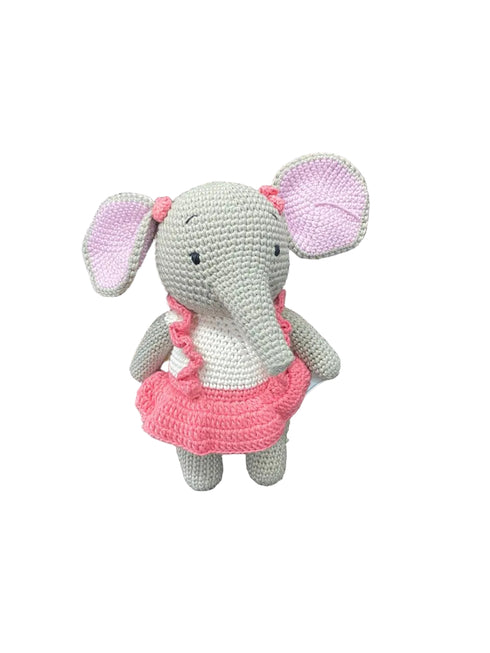 Crocheted elephant toy with a pink dress on a white board