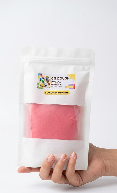 Hand holding a package of pink dough with a visible brand label on a white background