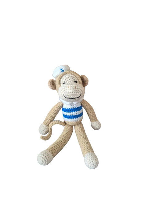A crocheted plush monkey toy wearing a white sailor hat and a blue-and-white striped shirt