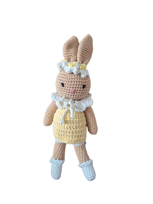 A handmade crocheted bunny doll with long ears, wearing a yellow dress, white ruffled collar