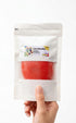 Hand holding a package of red play dough with a visible brand label on a white background