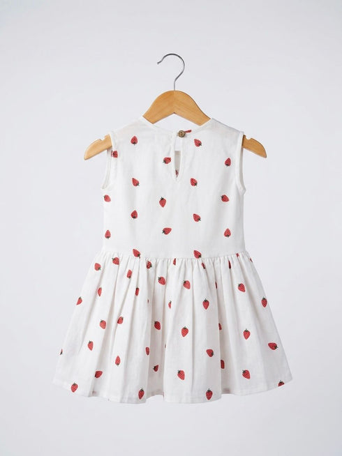White dress with red strawberry pattern on a hanger against a white background