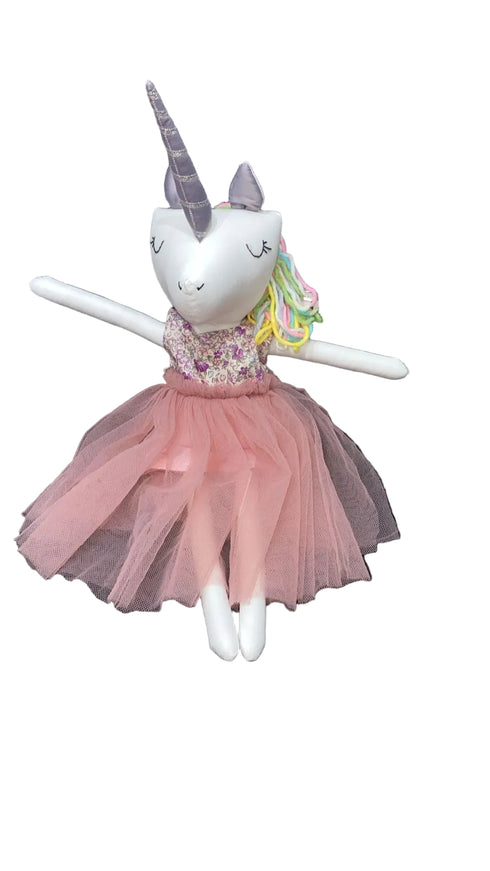 Stuffed unicorn toy with a pink dress sitting on a chair.