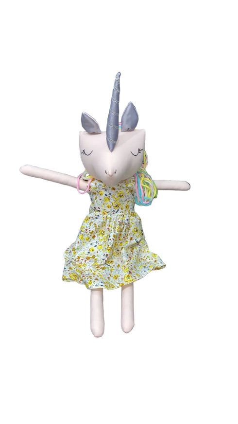 Stuffed toy with unicorn horn and floral dress on a chair