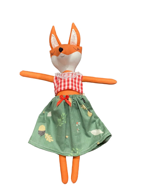 Stuffed fox toy with a red checkered shirt and green skirt on a white background