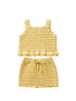 Yellow crochet baby top and shorts set on a beige surface with a neutral background.
