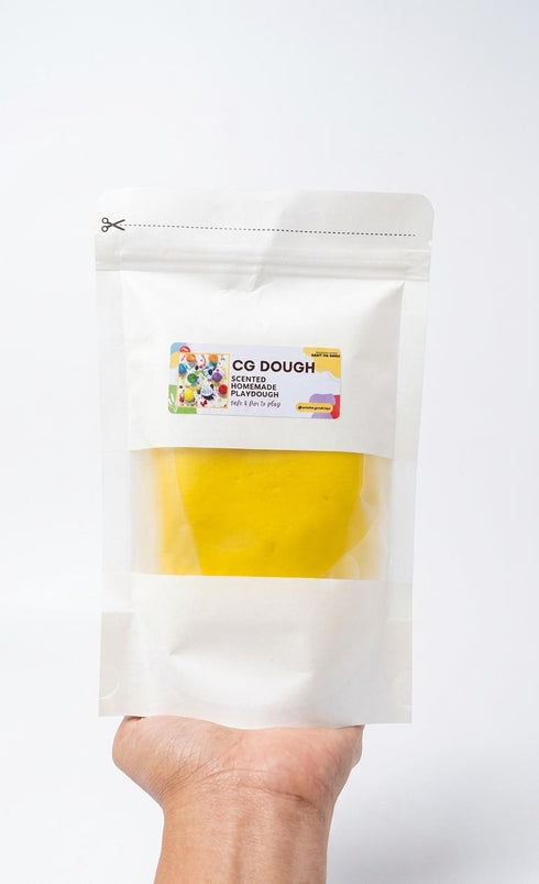 Hand holding a package of CG Dough with a visible label on a white background