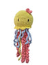 A handmade crocheted jellyfish toy. The toy has a yellow head with a small pink bow, black embroidered eyes, and long wavy tentacles in light blue, pink, and yellow.